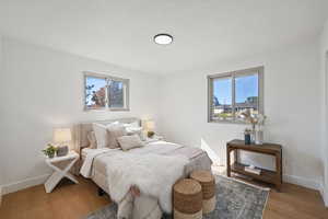 Bedroom with multiple windows, a textured ceiling, and hardwood / wood-style flooring