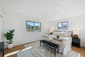 Bedroom featuring light hardwood / wood-style flooring, multiple windows, and a textured ceiling