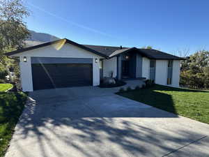 View of front of house featuring a mountain view, a front lawn, and a garage