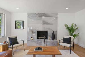 Living room with a tiled fireplace, a textured ceiling, and hardwood / wood-style floors