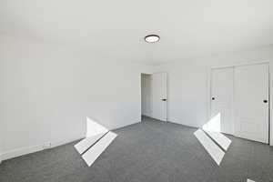 Unfurnished bedroom featuring a closet and dark colored carpet