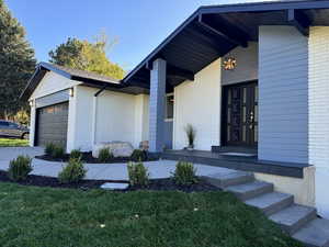 Entrance to property with a lawn and a garage