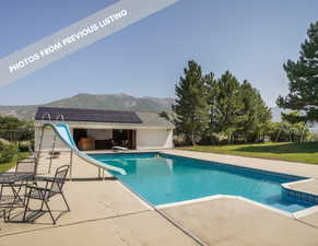 View of pool with a yard, a mountain view, a diving board, a water slide, and a patio area