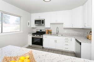 Kitchen featuring light hardwood / wood-style flooring, stainless steel appliances, sink, and white cabinets