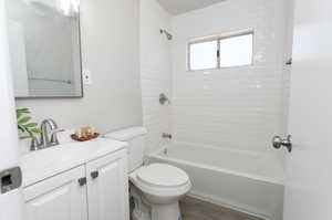 Full bathroom with tiled shower / bath, vanity, wood-type flooring, and toilet