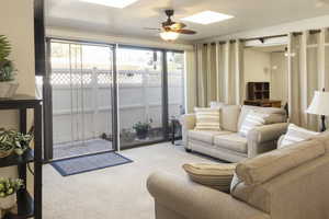 Carpeted living room featuring ceiling fan and a wealth of natural light