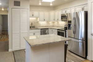 Kitchen with appliances with stainless steel finishes, light hardwood / wood-style flooring, and white cabinets