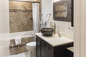 Full bathroom featuring vanity, shower / bath combo with shower curtain, toilet, and tile patterned flooring