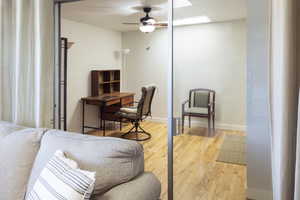 Home office with light hardwood / wood-style flooring and ceiling fan