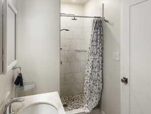 Bathroom with toilet, curtained shower, sink, and tile patterned floors