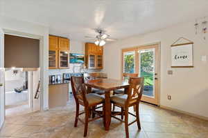 Dining area with ceiling fan, a textured ceiling, and light tile patterned flooring