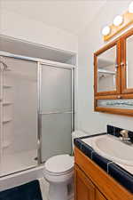 Bathroom featuring a shower with door, vanity, toilet, and tile patterned flooring