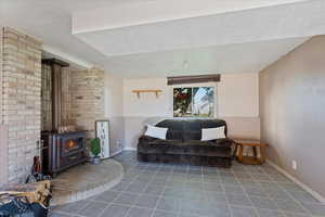 Sitting room with dark tile patterned floors, a textured ceiling, and a wood stove