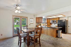 Tiled dining area with a textured ceiling, sink, and ceiling fan