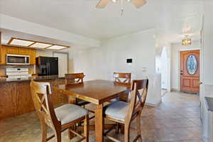 Tiled dining area with ceiling fan with notable chandelier