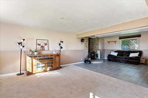 Living room featuring a textured ceiling, a wood stove, and carpet floors