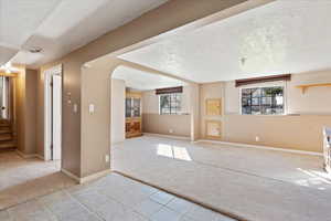 Unfurnished living room with a wealth of natural light, a textured ceiling, and light colored carpet