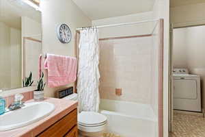 Full bathroom featuring toilet, washer / clothes dryer, shower / tub combo with curtain, and vanity