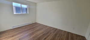 Unfurnished bedroom featuring a textured ceiling, dark hardwood / wood-style flooring, and baseboard heating