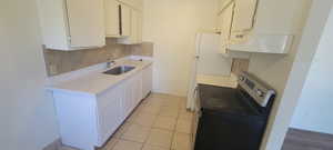 Kitchen with decorative backsplash, white cabinets, white dishwasher, stainless steel electric range oven, and sink