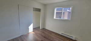 Unfurnished bedroom with dark wood-type flooring, a closet, a textured ceiling, and a baseboard heating unit