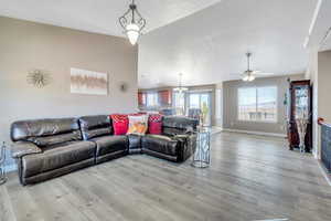 Living room with light hardwood / wood-style flooring and ceiling fan with notable chandelier