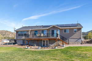 Back of property featuring french doors, solar panels, a lawn, and a deck with mountain view