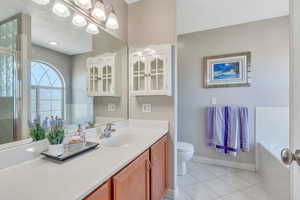 Bathroom featuring a tub to relax in, vanity, toilet, and tile patterned floors