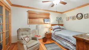 Bedroom with ornamental molding, hardwood flooring, and ceiling fan