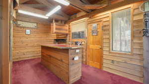 Interior space featuring wood walls, wooden ceiling, lofted ceiling with beams, and dark colored carpet