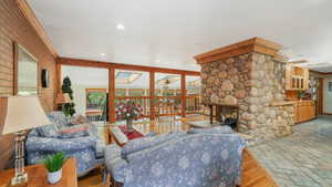 Living room featuring light hardwood / hardwood and slate flooring, crown molding, multiple skylights, and a stone fireplace