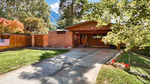 View of front of house featuring brick siding, fence, and a front yard