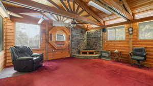 Living area with carpet, ceiling fan, wood ceiling, and wooden walls