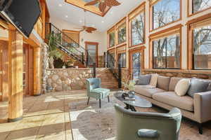 Living room featuring high vaulted ceiling, ceiling fan, and a generous amount of sunlight