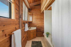 Bathroom with toilet, tile patterned flooring, wooden walls, and vanity