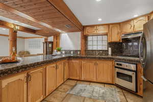 Second kitchen with newer updated countertops, wooden ceiling, stainless steel appliances, beamed ceiling, and backsplash