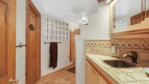 Three quarter bathroom with vanity, western saloon style doors, and decorative backsplash