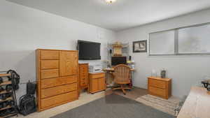 Bedroom used as home office with light colored carpet