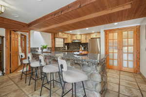 Kitchen with stainless steel refrigerator, a breakfast bar, french doors, lower level laundry, decorative backsplash, and light brown cabinets