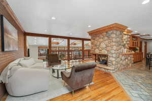 Living room with a stone fireplace, beamed ceiling, and wood-type flooring