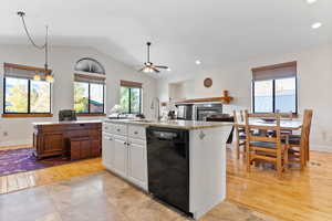 Kitchen featuring lofted ceiling, white cabinets, black dishwasher, a kitchen island with sink, and light hardwood / wood-style flooring