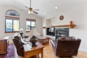 Living room featuring light hardwood / wood-style flooring, lofted ceiling, and ceiling fan