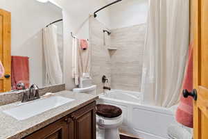 Full bathroom featuring vanity, toilet, and shower / bathtub combination with curtain