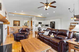 Living room featuring ceiling fan, sink, light wood-type flooring, and vaulted ceiling