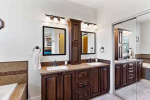 Bathroom featuring vanity, tiled tub, and tile patterned floors