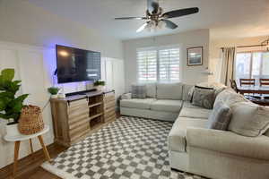 Living room featuring ceiling fan, plenty of natural light, and  laminate wood-style floors