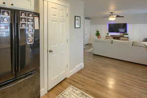 Kitchen featuring light  laminate  wood-style floors, white cabinetry, black refrigerator, and ceiling fan