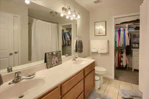 Bathroom with vanity, a shower with shower curtain, toilet, and tile patterned floors