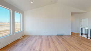 Unfurnished room featuring light hardwood / wood-style floors and lofted ceiling