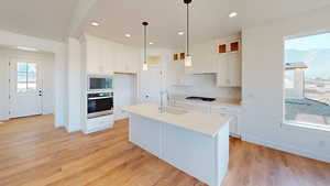 Kitchen featuring sink, light hardwood / wood-style flooring, a center island with sink, and appliances with stainless steel finishes